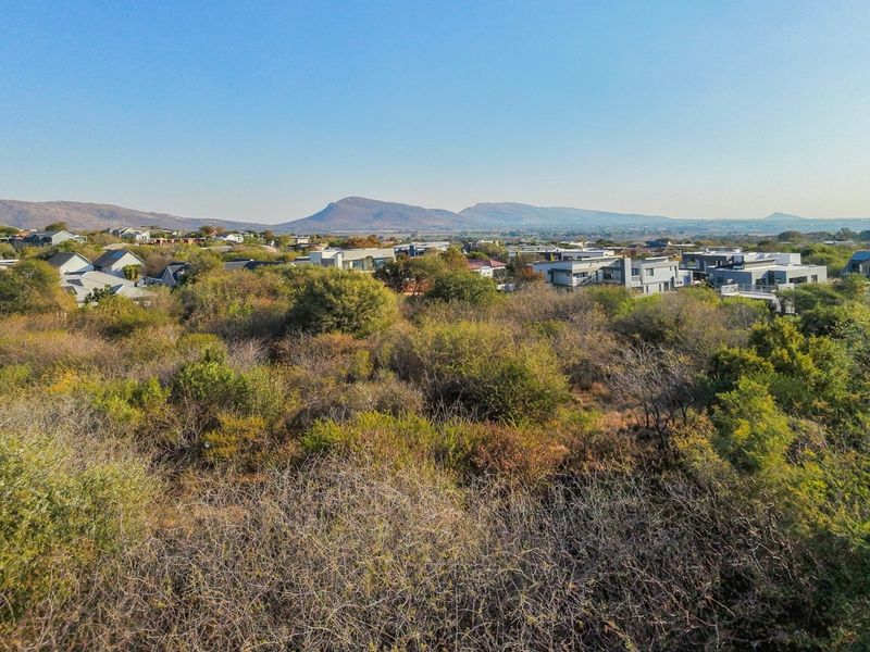 An aerial view of the vacant residential land, showcasing the surrounding neighborhood and distant mountain landscape.