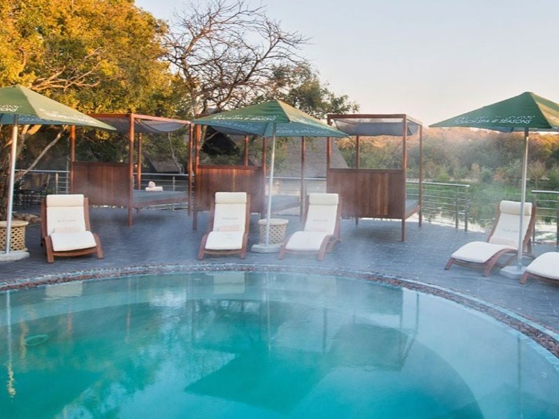 A well-maintained outdoor pool area featuring stone paving, a circular swimming pool, and metal safety railings overlooking a natural landscape.