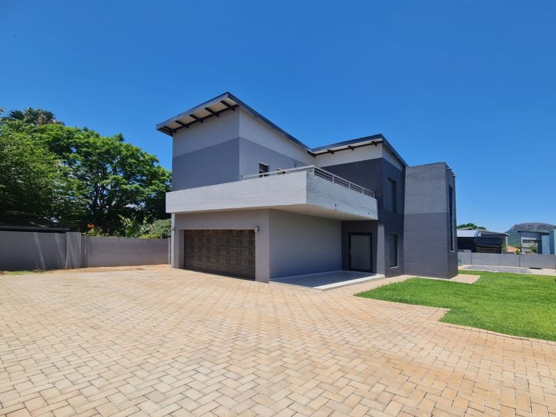 Modern double-story residential property featuring a paved driveway, integrated garage, and an upper-level balcony with clean architectural lines.