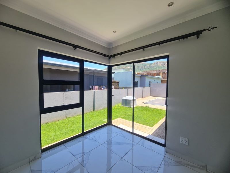 Bright living area featuring modern tiled flooring and large black aluminium sliding doors providing direct access to the rear garden.
