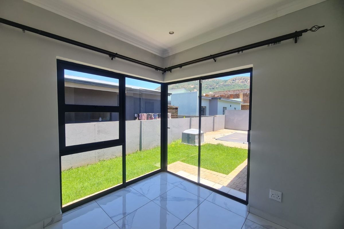 Bright living area featuring modern tiled flooring and large black aluminium sliding doors providing direct access to the rear garden.