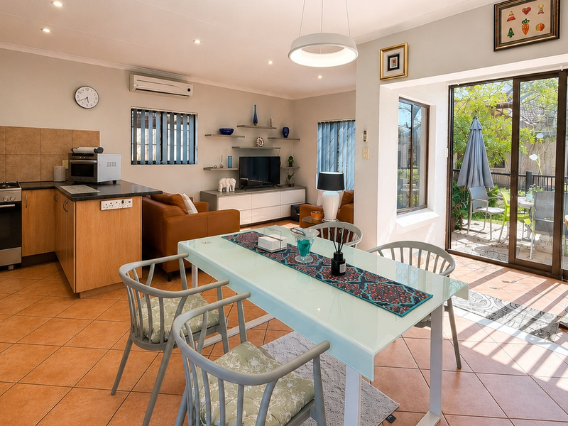 Open-plan living and kitchen area featuring tiled floors, built-in cabinetry, and sliding glass doors providing direct access to the outdoor patio.