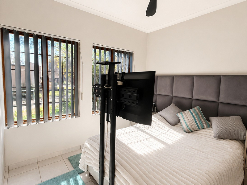 A well-lit bedroom featuring tiled flooring, built-in wardrobes, and vertical blinds, offering a functional and comfortable living space.