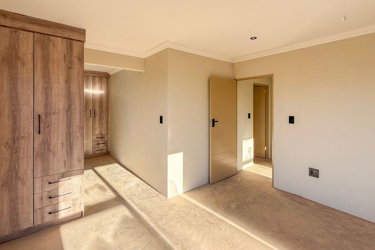 A bright, empty bedroom featuring modern built-in cupboards, neutral wall finishes, and clean flooring, offering a versatile space ready for personalization.