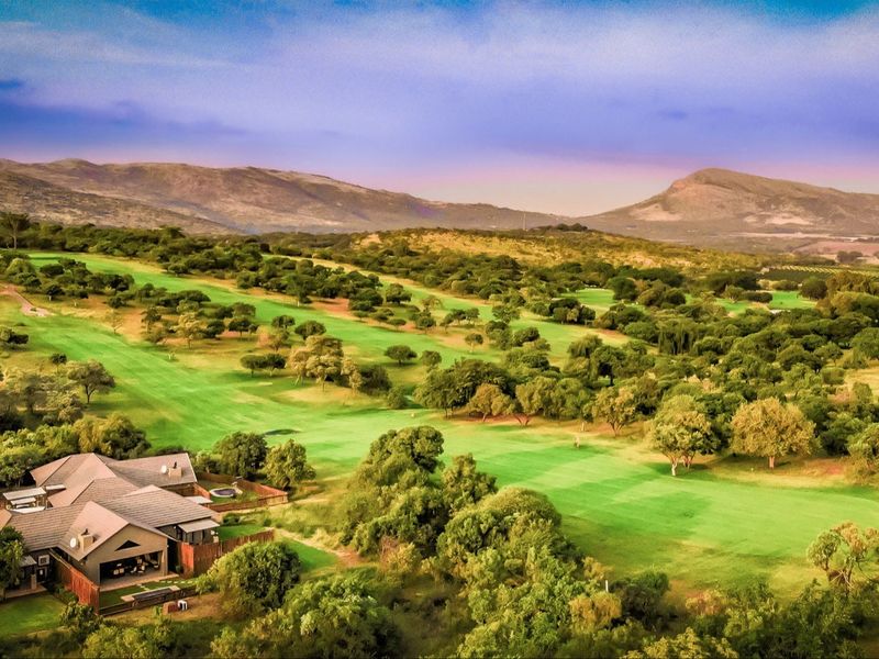 An aerial view of a residential property situated on a scenic golf course with expansive mountain views in the background.