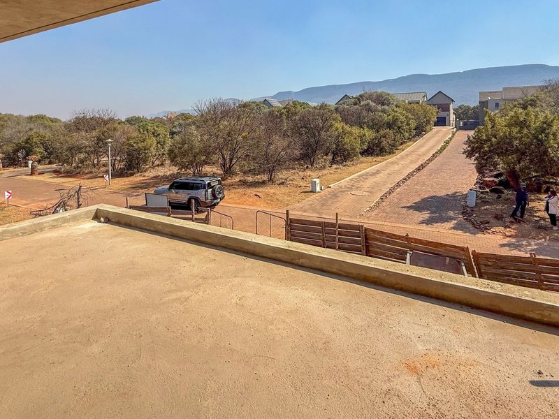 An unfinished concrete balcony offering an elevated view of the surrounding estate landscape and driveway.