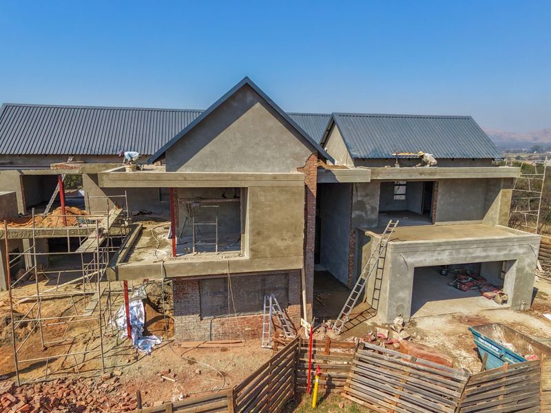Aerial view of a residential property under construction, showing the structural shell, metal roofing, and ongoing building works on site.