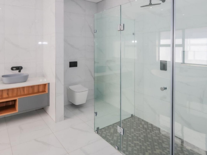 Modern, high-end bathroom featuring a double vanity, wall-mounted toilet, and a spacious walk-in shower with premium marble-look tiling and contemporary fixtures.