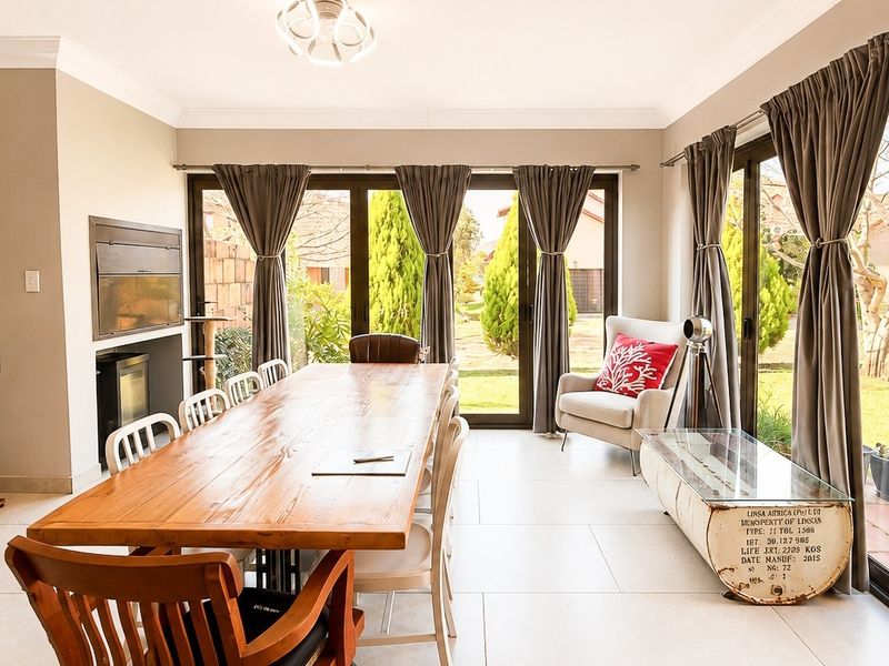 Spacious dining room featuring large sliding glass doors that open to the garden, tiled flooring, and a built-in fireplace.