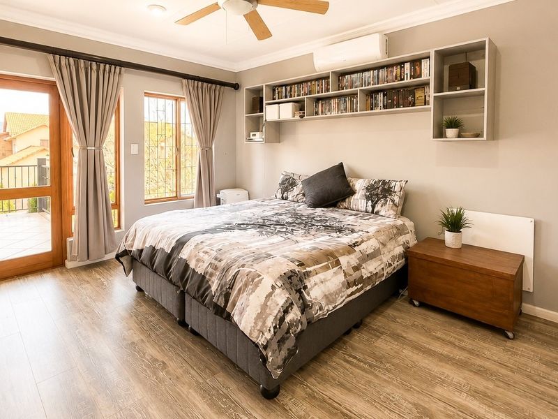 Spacious bedroom featuring laminate flooring, built-in shelving, a ceiling fan, air conditioning, and direct access to a private balcony.