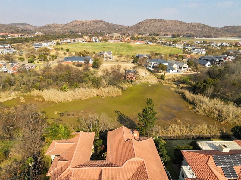 Aerial view of a residential property featuring terracotta tiled roofs and solar panels, overlooking a scenic estate landscape with natural vegetation.