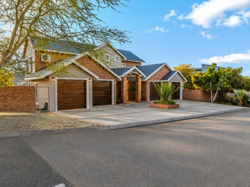 A well-maintained double-story residential property featuring a triple garage, brick facade, and a paved driveway.