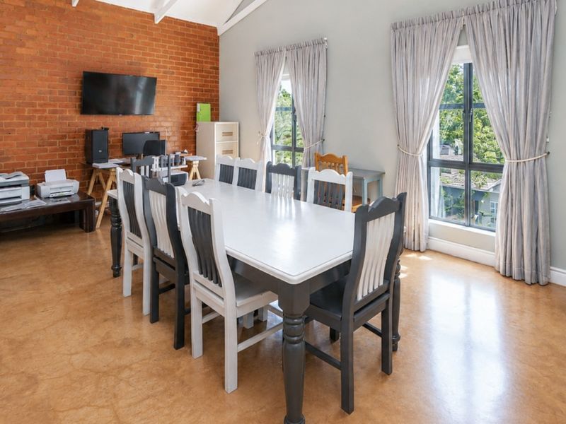 Spacious dining room featuring an exposed brick feature wall, vaulted ceilings, and polished concrete flooring, offering a bright and contemporary living space.
