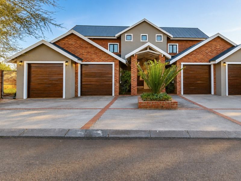 A well-maintained residential property featuring a triple garage, brick facade, and a paved driveway with a central landscaped planter.