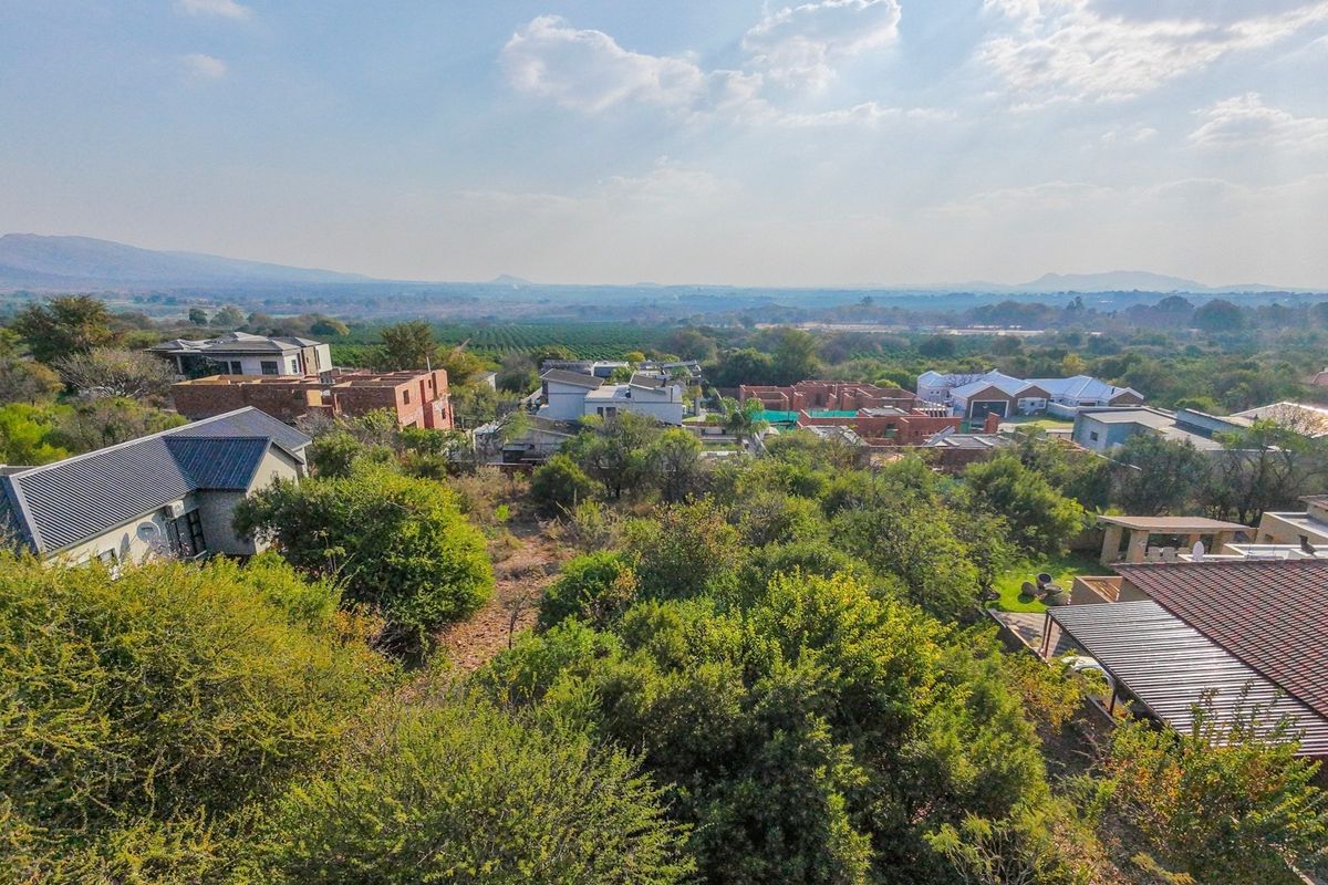 An aerial view of a residential estate featuring established vegetation and surrounding landscape views.