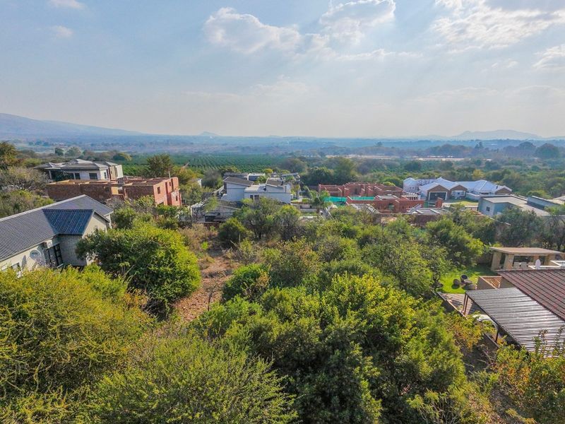 An aerial view of a residential estate featuring established vegetation and surrounding landscape views.