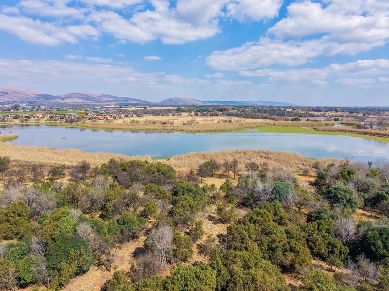An aerial view of the vacant residential land featuring natural vegetation and scenic lake views.