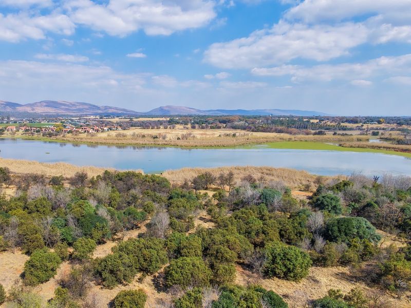 An expansive aerial view of the vacant residential land featuring natural vegetation, a scenic lake, and distant mountain vistas.