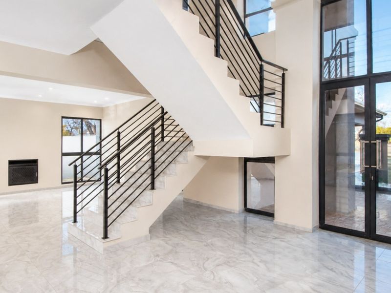 Spacious entrance hall featuring a modern staircase with metal balustrades, polished marble flooring, and large glass doors leading to the exterior.