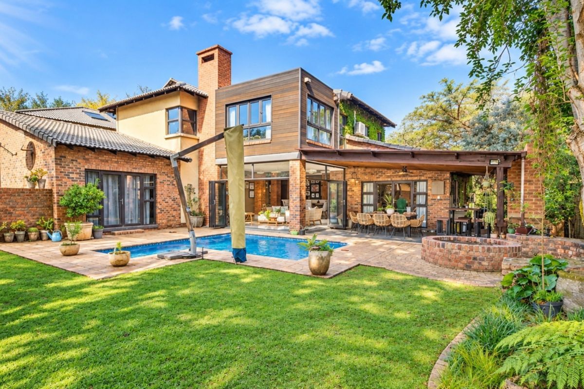 Spacious rear exterior featuring a swimming pool, covered patio area, brick fire pit, and a mix of brick and timber architectural finishes.