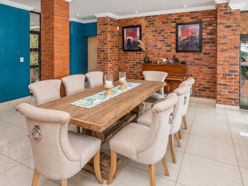 Spacious dining area featuring exposed brick walls, tiled flooring, and recessed lighting, with direct access to an outdoor patio through sliding glass doors.