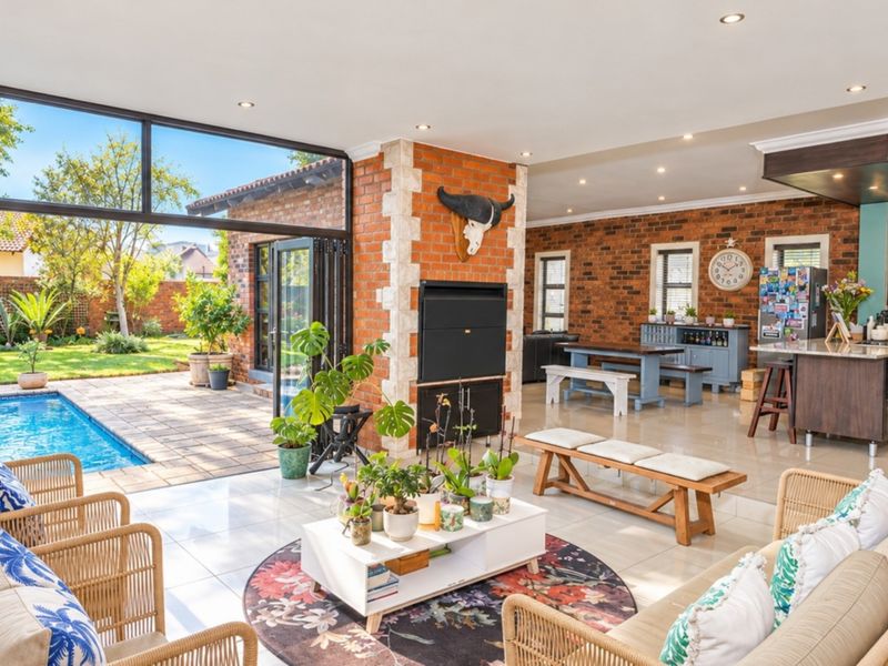Spacious open-plan living area featuring exposed brick walls, a built-in fireplace, and seamless flow to the outdoor patio and swimming pool area.