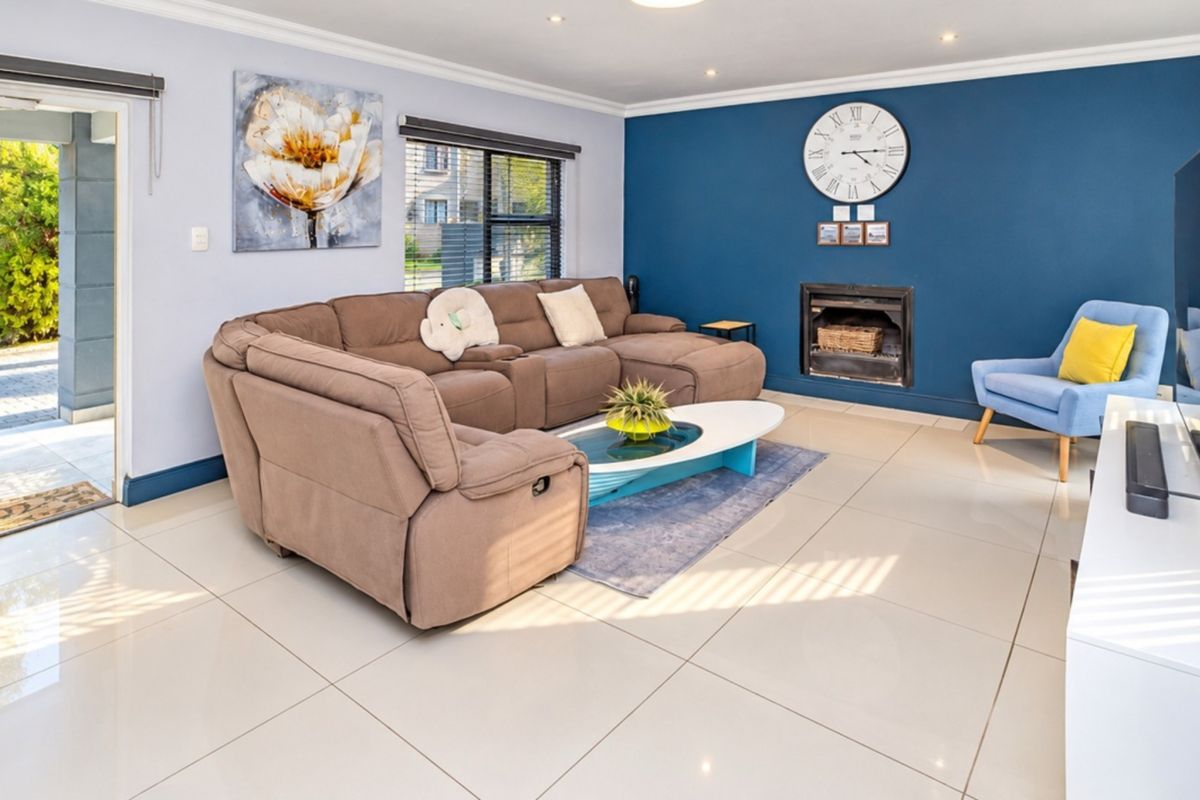 A bright and spacious living room featuring large format floor tiles, a built-in fireplace, and direct access to an outdoor patio area.