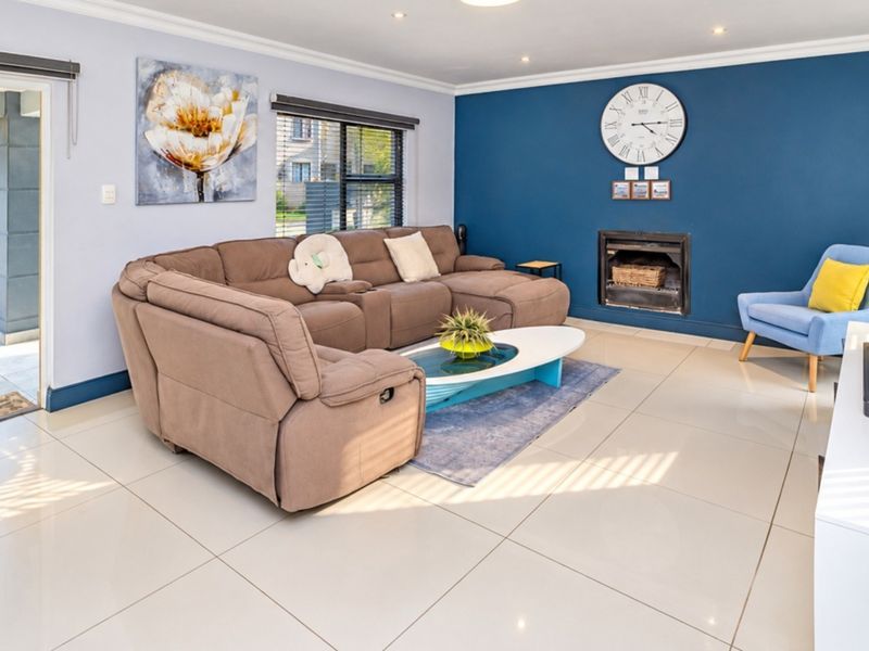 A bright and spacious living room featuring large format floor tiles, a built-in fireplace, and direct access to an outdoor patio area.