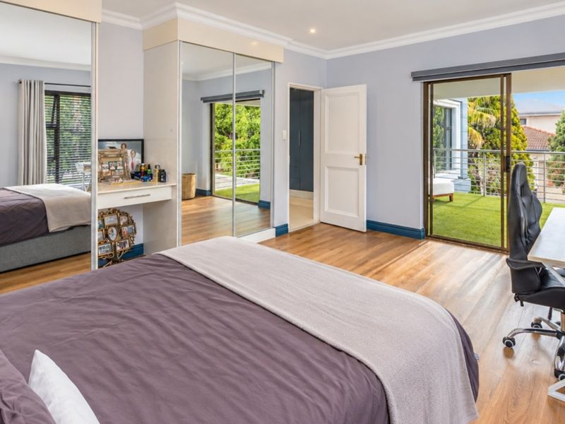 Spacious bedroom featuring hardwood flooring, built-in mirrored wardrobes, and direct access to a private balcony through sliding glass doors.