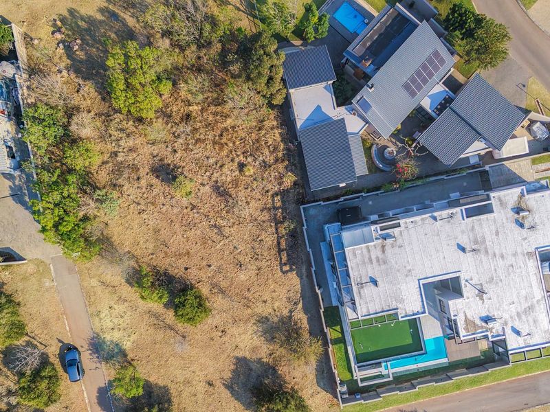 Aerial view of a residential property featuring multiple buildings, solar panels, a swimming pool, and surrounding landscaped grounds.