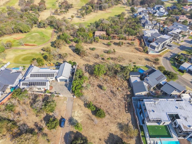 Aerial view of a vacant residential plot situated within a developed estate, adjacent to a golf course and established neighboring properties.