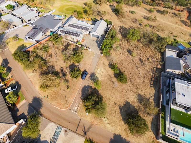 Aerial view of a residential vacant land plot featuring a paved driveway and surrounding established neighborhood infrastructure.