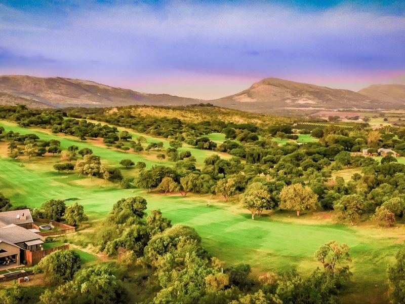 Aerial view of a residential property situated on a scenic golf course with expansive mountain views in the background.