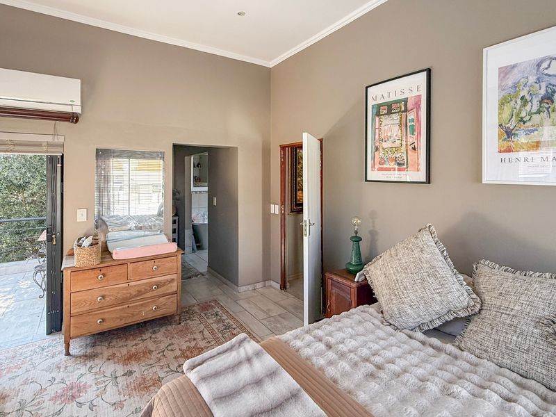 Spacious bedroom featuring neutral walls, tiled flooring, an air conditioning unit, and direct access to a private balcony and en-suite bathroom.