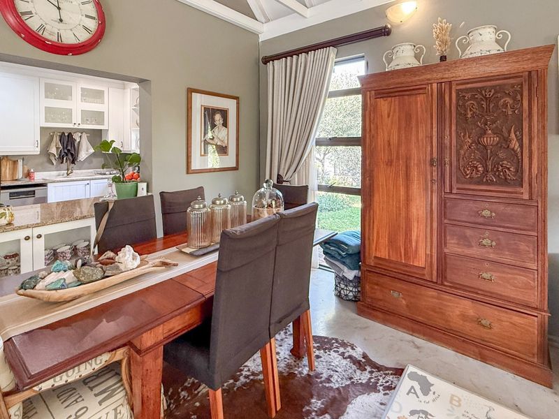 Open-plan dining area featuring a wood-burning stove, exposed beam ceiling, and a seamless transition into a well-appointed kitchen with granite countertops.