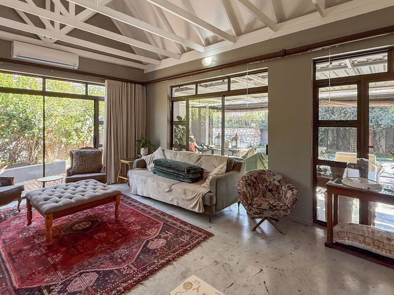 Spacious living room featuring a high vaulted ceiling with exposed beams, polished concrete floors, and large sliding glass doors providing ample natural light.