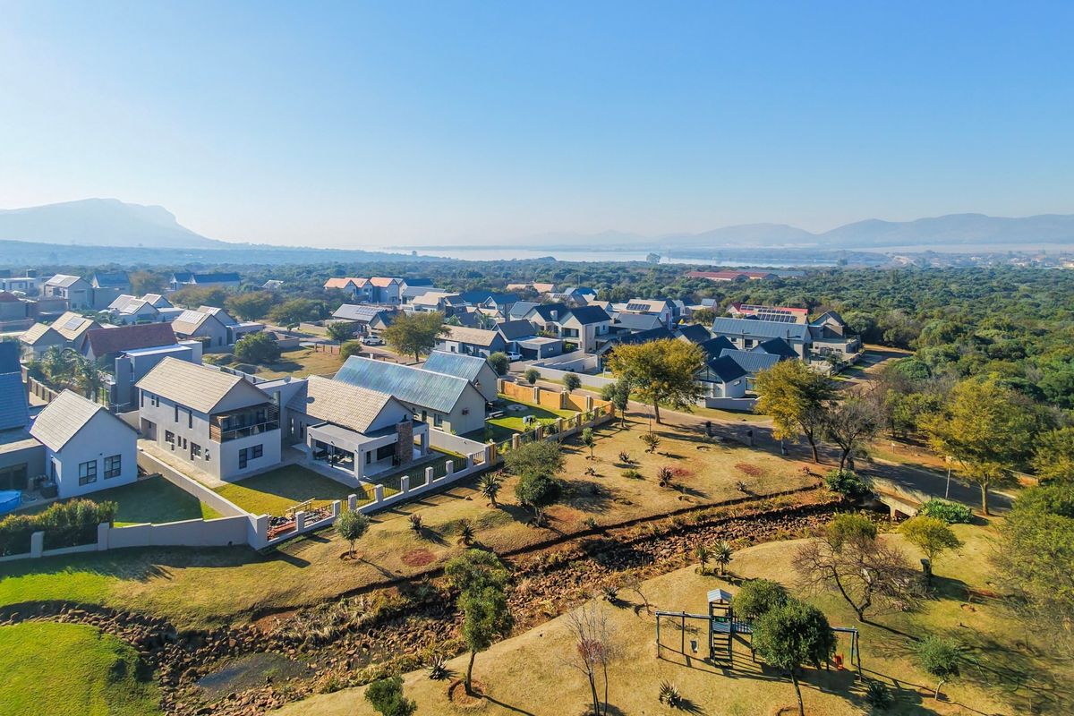 An aerial view of a residential estate featuring modern homes, landscaped surroundings, and scenic landscape views in the distance.