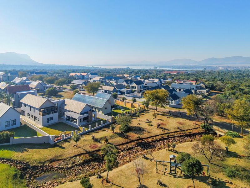 An aerial view of a residential estate featuring modern homes, landscaped surroundings, and scenic landscape views in the distance.