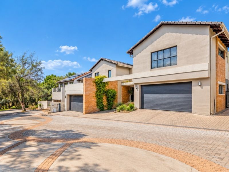 Front view of a modern residential property featuring a paved driveway, double garage, and attractive brick and plaster exterior finishes.