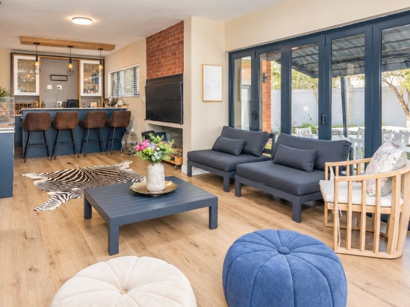 Spacious open-plan living area featuring a built-in bar, exposed brick wall, and large bi-fold doors providing seamless access to the outdoor patio.