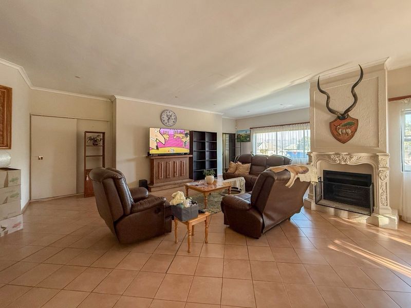 Spacious living room featuring tiled flooring, an ornate fireplace, and large windows allowing for natural light.