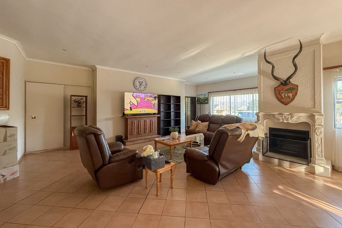 Spacious living room featuring tiled flooring, an ornate fireplace, and large windows allowing for natural light.