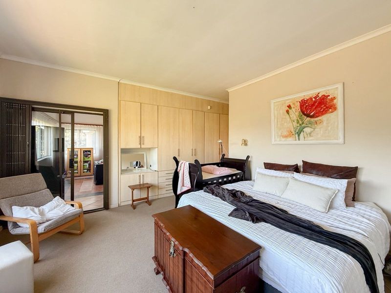 Spacious bedroom featuring neutral walls, carpeted flooring, and extensive built-in cabinetry with an integrated vanity area.