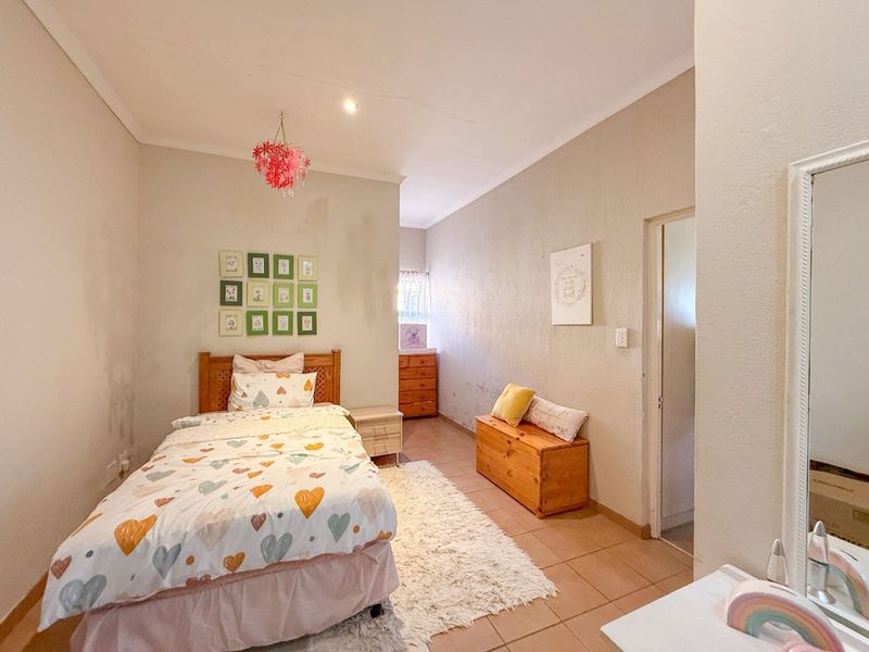 A bedroom featuring tiled flooring and coved ceilings, currently utilized as a child's room with neutral wall finishes.