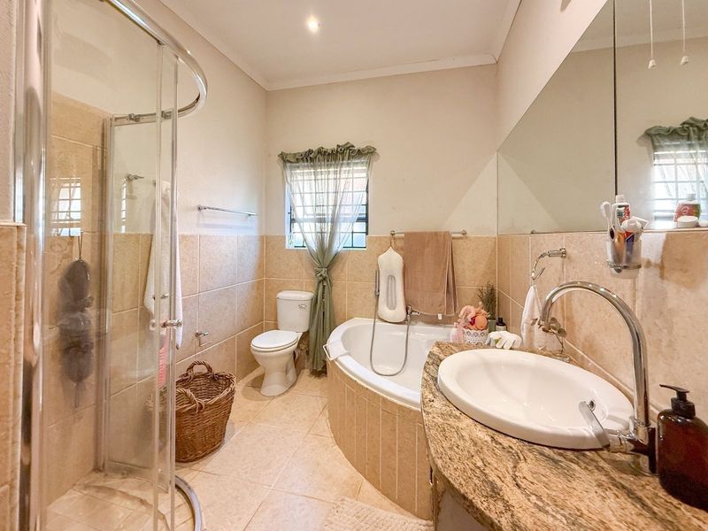 A functional bathroom featuring a corner bathtub, separate glass shower enclosure, and a vanity with a granite countertop.