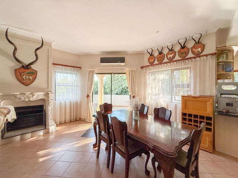 Spacious dining room featuring tiled flooring, a decorative fireplace, and direct access to an outdoor patio area through sliding glass doors.