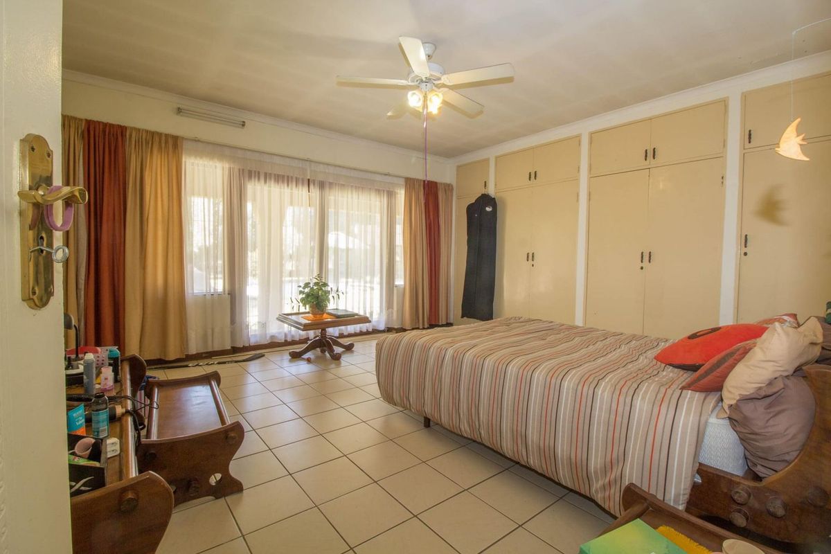 Spacious bedroom featuring built-in cupboards, tiled flooring, and large sliding glass doors providing natural light and access to the exterior.
