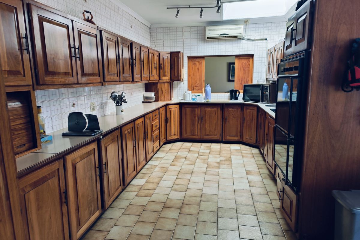 Spacious kitchen featuring extensive wooden cabinetry, tiled flooring, built-in double oven, and a skylight providing natural illumination.