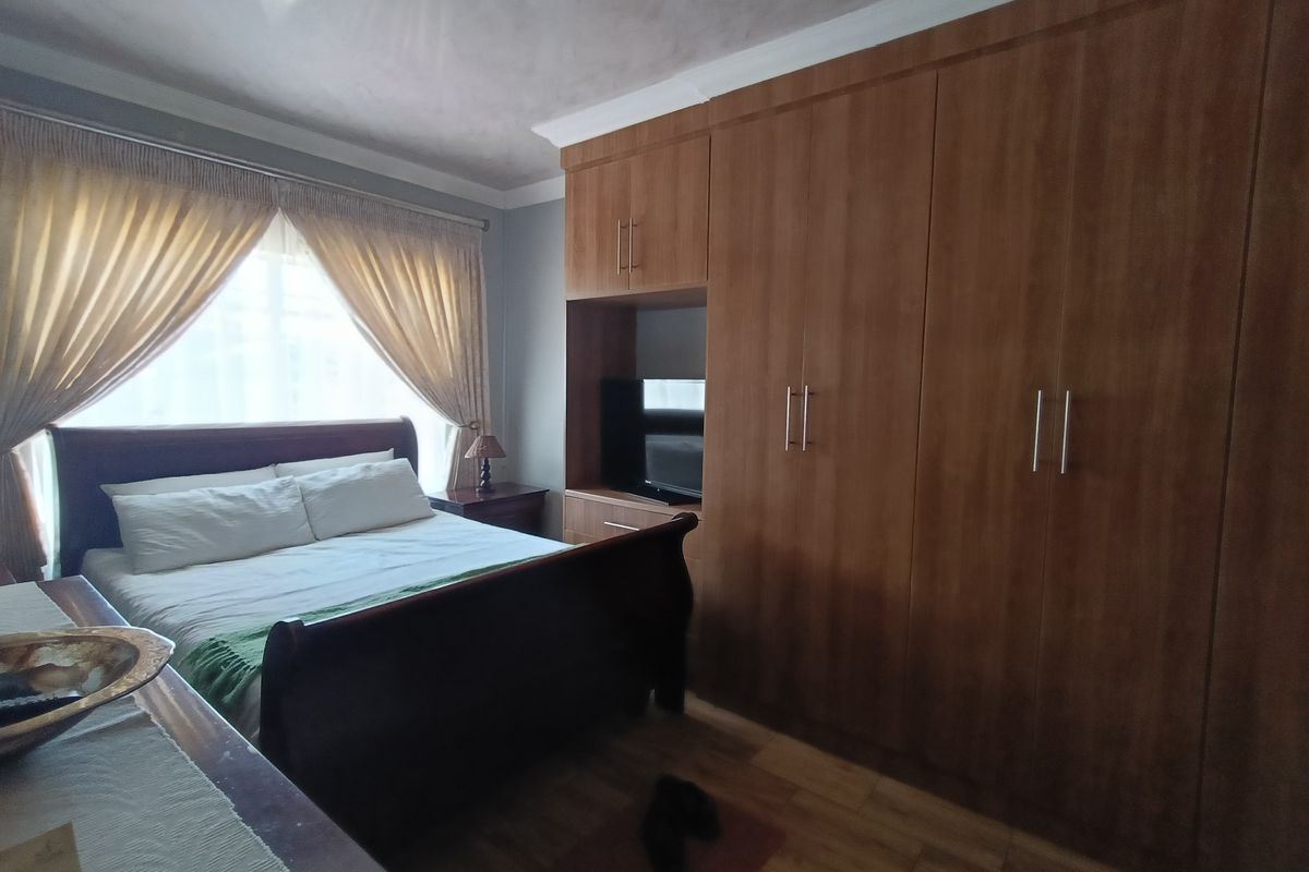 A bedroom featuring built-in wooden cabinetry with integrated shelving and laminate flooring.