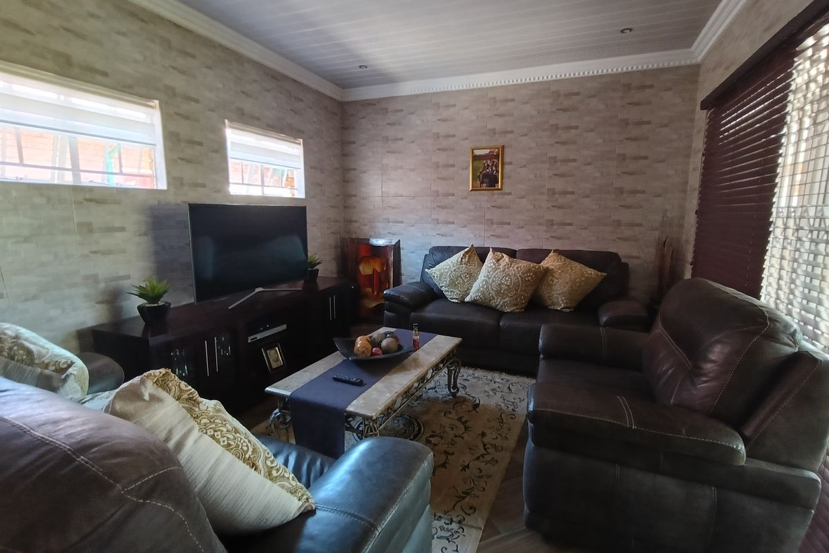 A comfortable living room featuring tiled wall finishes, recessed lighting, and large windows with fitted blinds.